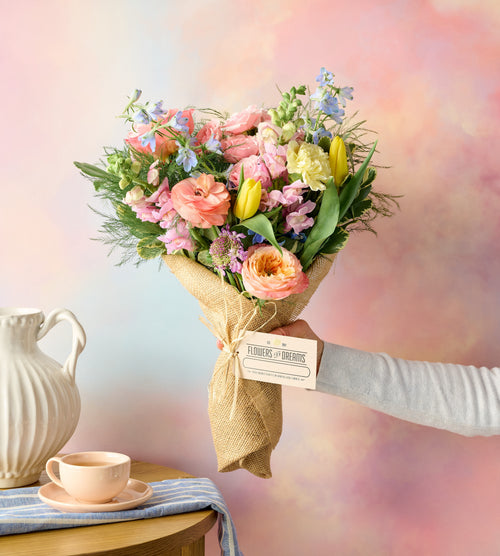 Person holding a lush Spring floral bouquet, soft blurred background
